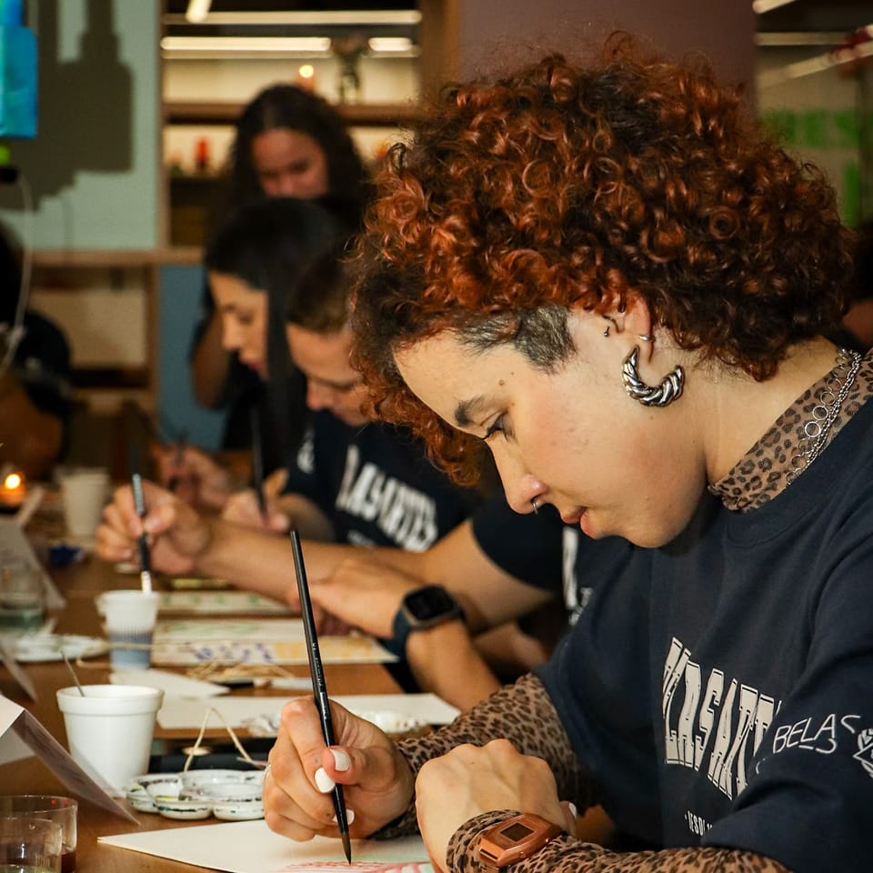 Turma concentrada em aula de pintura com pincel e tinta