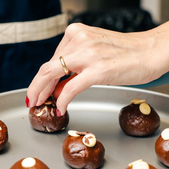 Mão finalizando doces de chocolate em aula de confeitaria